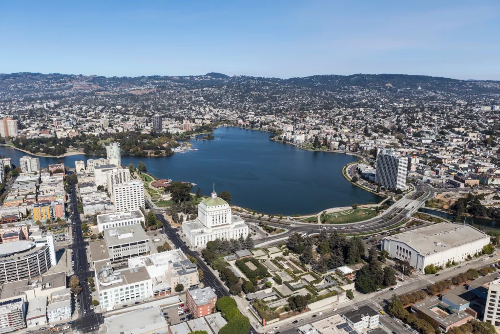 Areal view of downtown Oakland and Lake Merritt with surrounding hills in background.